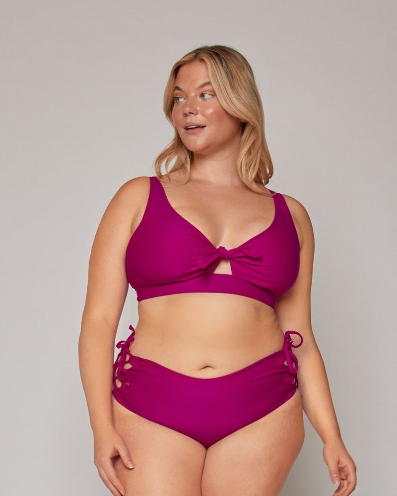 Front of a model wearing a size 10|12 Lola Side-Tie Bottoms in Orchid by Wild Isles Swim. | dia_product_style_image_id:284917